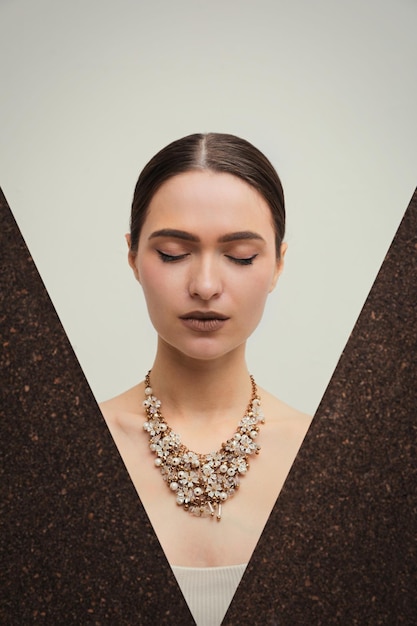 Hermosa mujer joven con collar de lujo posando sobre fondo claro