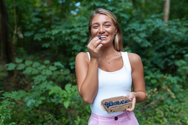 Hermosa mujer joven come arándanos Mujer comiendo vitaminas BACCcerrar Profundidad superficial Primer plano