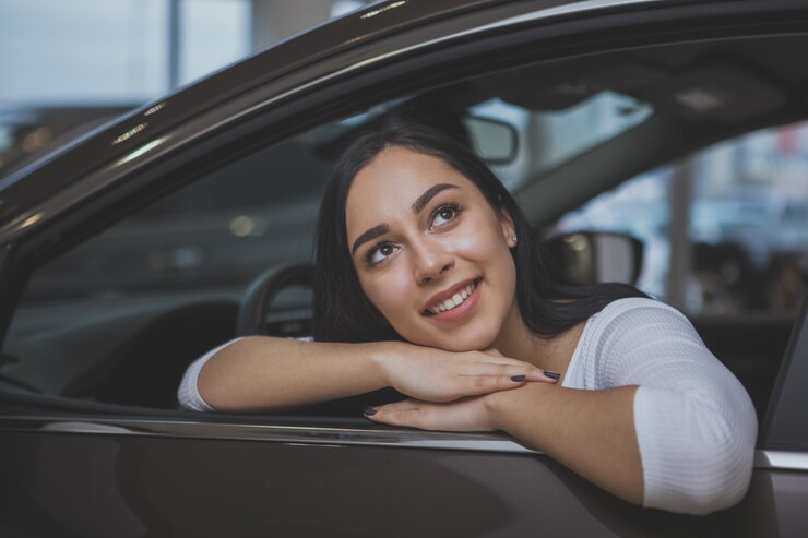 Foto hermosa mujer joven compra un auto nuevo en el concesionario