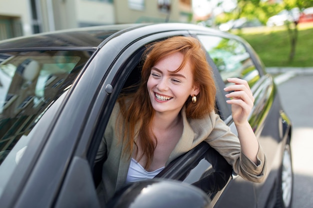 Hermosa mujer joven conduciendo su auto nuevo al atardecer