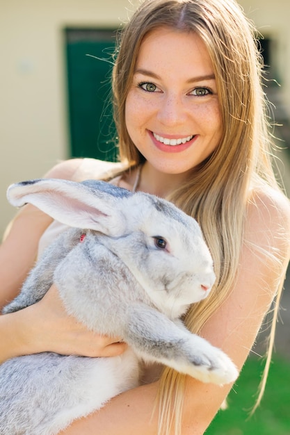 Hermosa mujer joven con conejito en la granja retrato de mujer joven posando con conejo