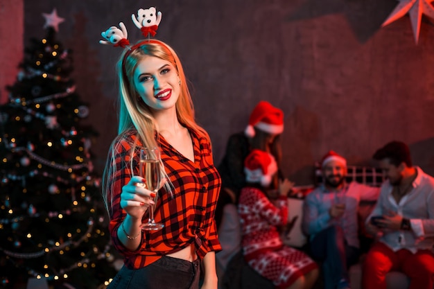 Hermosa mujer joven con copa de champán en la fiesta de Navidad