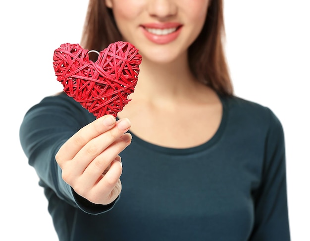 Hermosa mujer joven con corazón de mimbre decorativo sobre fondo blanco closeup