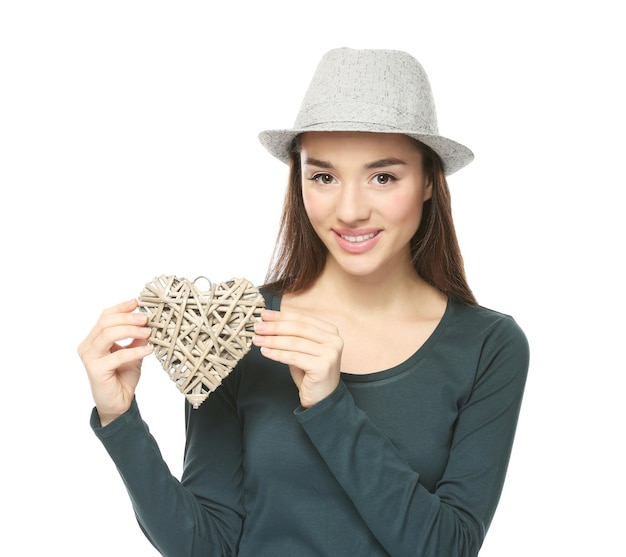 Hermosa mujer joven con corazón de mimbre decorativo sobre fondo blanco.