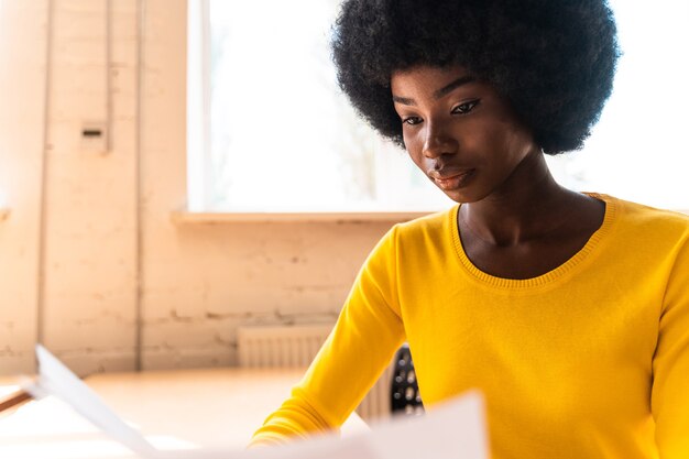 Hermosa mujer joven con el corte de pelo afro trabajando en la oficina