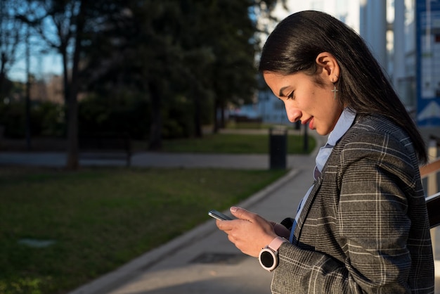 Hermosa mujer joven a la derecha que usa el teléfono usa una chaqueta gris y un reloj inteligente