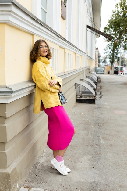 Hermosa mujer joven en elegante cárdigan amarillo en la calle de la ciudad