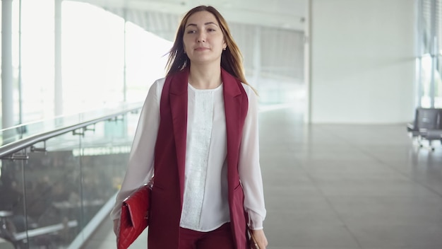 Hermosa mujer joven en un elegante traje con bolsa apresurándose a abordar el avión en el aeropuerto