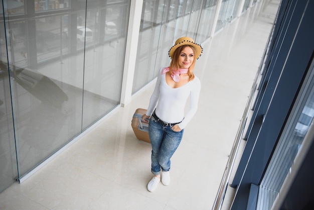 Hermosa mujer joven con equipaje en el aeropuerto