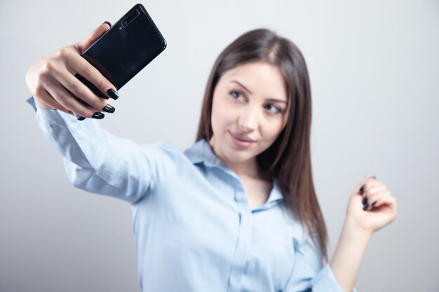 Hermosa mujer joven está haciendo foto selfie con smartphone.