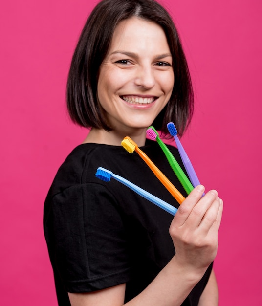 Hermosa mujer joven feliz con cepillos de dientes de diferentes colores