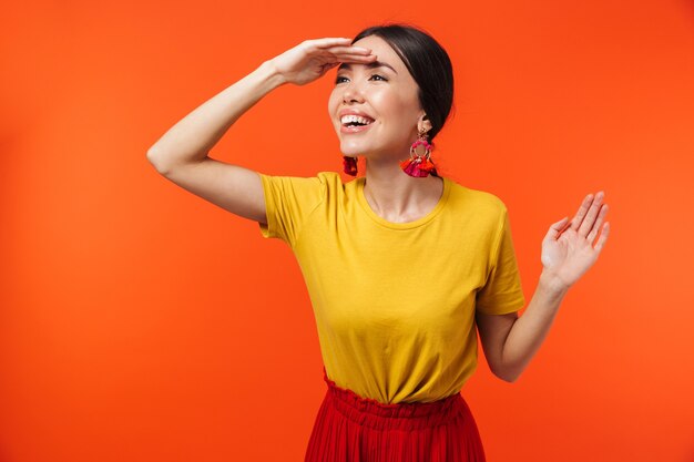 hermosa mujer joven feliz emocionada posando aislada sobre pared naranja.