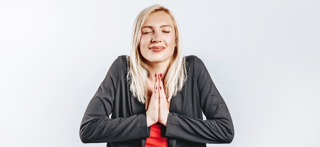 Hermosa mujer joven feliz sonríe en la pared gris aislada