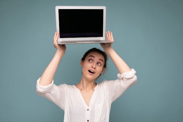 Hermosa mujer joven feliz sonriente con ordenador portátil mirando netbook divirtiéndose vistiendo ropa casual elegante aislada sobre fondo de pared. Mock up, copie el espacio, recorte