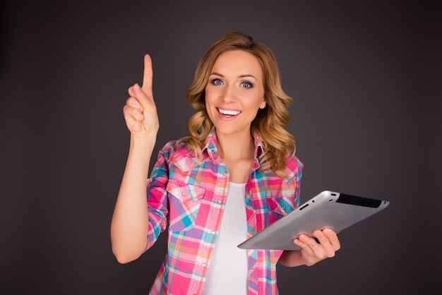 Hermosa mujer joven feliz sosteniendo la tableta y tener una idea