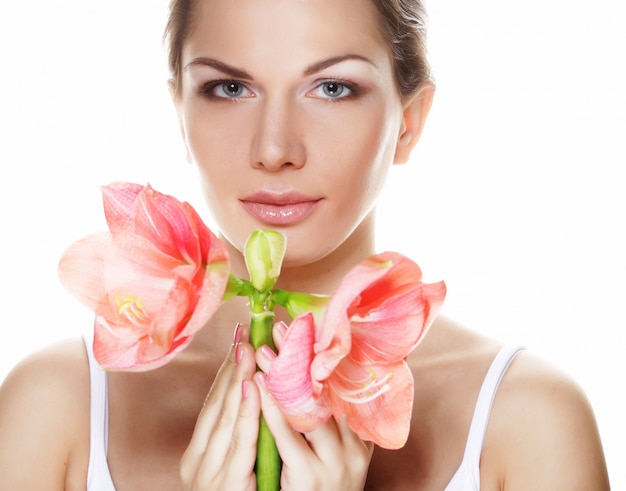 Hermosa mujer joven con flor rosa sobre blanco