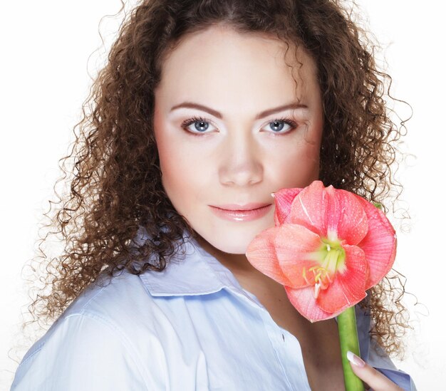 Hermosa mujer joven con flor rosa sobre fondo blanco