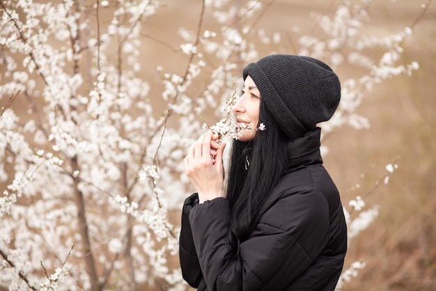 Hermosa mujer joven en el floreciente jardín de flores de cerezo