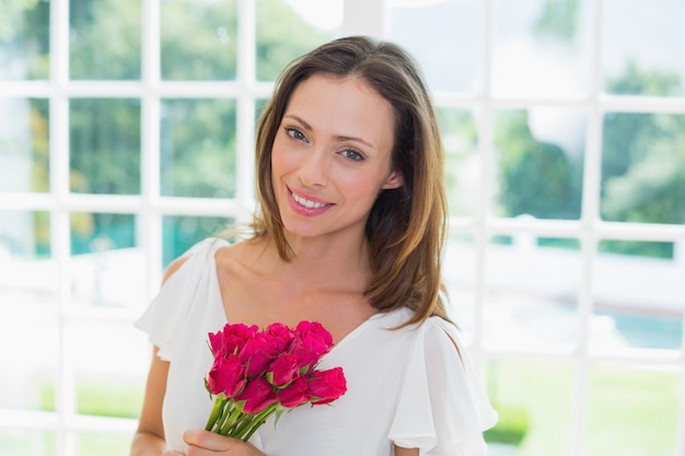 Hermosa mujer joven con flores en casa