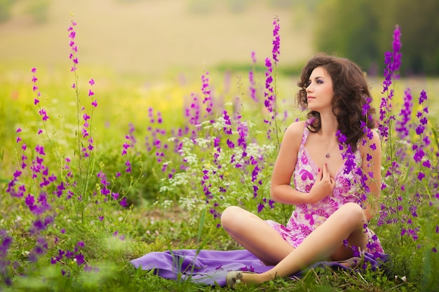 Hermosa mujer joven en flores de color púrpura al aire libre