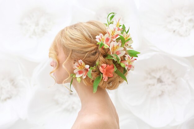 Hermosa mujer joven con flores en el pelo en blanco