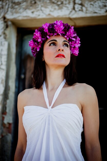 Hermosa mujer joven con flores rosadas y vestido blanco.