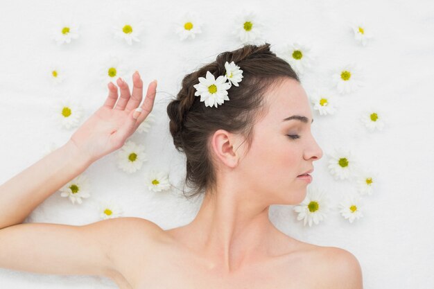 Hermosa mujer joven con flores en el salón de belleza