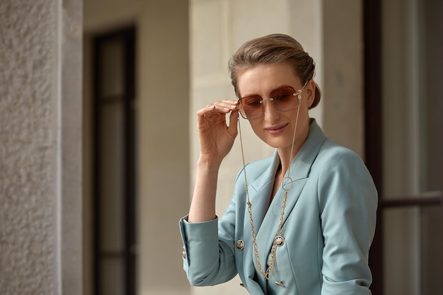 Hermosa mujer joven con gafas de sol en una chaqueta de moda camina por la ciudad Retrato de estilo de vida al aire libre