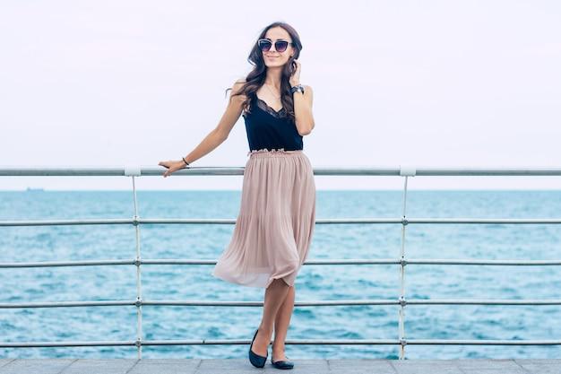 Hermosa mujer joven en gafas de sol y vestido en barco de crucero de lujo. Mujer de vacaciones de crucero disfrutando de viajes en el mar. Mujer feliz libre mirando al mar