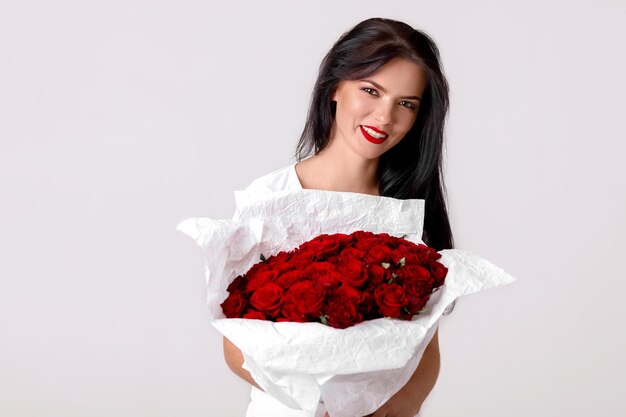 Hermosa mujer joven con un gran ramo de rosas rojas