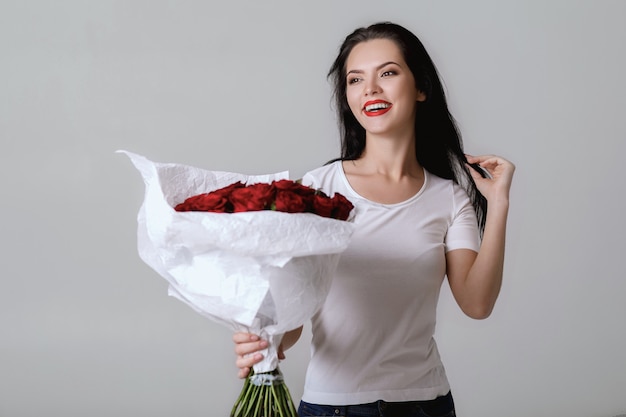 Hermosa mujer joven con un gran ramo de rosas rojas