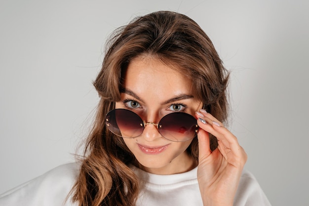 Foto hermosa mujer joven con grandes gafas de sol cerrar retrato sobre fondo blanco