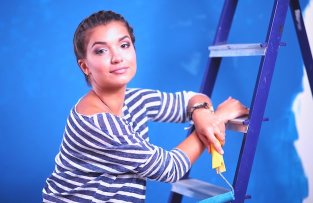 Hermosa mujer joven haciendo pintura mural de pie en la escalera