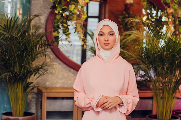 Hermosa mujer joven con un hijab rosa.