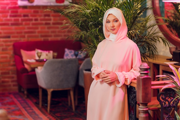 Hermosa mujer joven con un hijab rosa.
