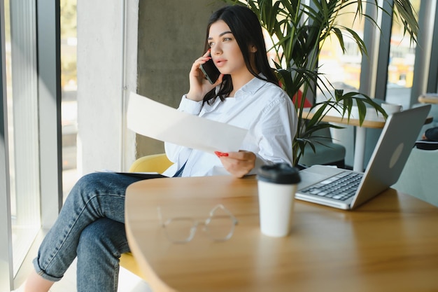 Hermosa mujer joven independiente que usa una computadora portátil sentada en la mesa del café Chica sonriente feliz trabajando en línea o estudiando y aprendiendo mientras usa el concepto de personas de negocios de trabajo independiente portátil