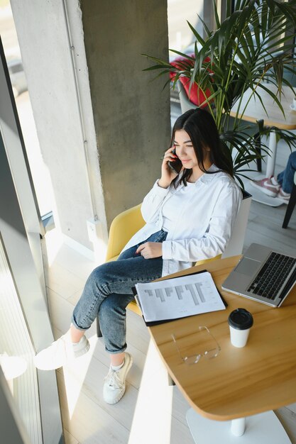 Hermosa mujer joven independiente que usa una computadora portátil sentada en la mesa del café Chica sonriente feliz trabajando en línea o estudiando y aprendiendo mientras usa el concepto de personas de negocios de trabajo independiente portátil