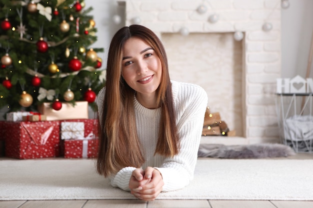 Hermosa mujer joven en un interior de Navidad con lugar de regalos para texto