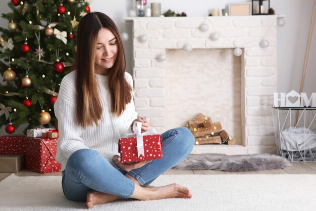 Hermosa mujer joven en un interior de Navidad con lugar de regalos para texto