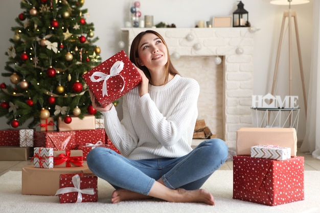 Hermosa mujer joven en un interior de Navidad con lugar de regalos para texto