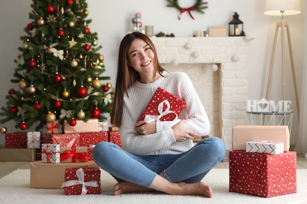 Hermosa mujer joven en un interior de Navidad con lugar de regalos para texto