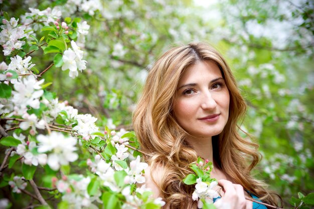 Hermosa mujer joven en jardín floreciente