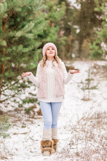 Hermosa mujer joven en jeans y chaqueta rosa en bosque de invierno