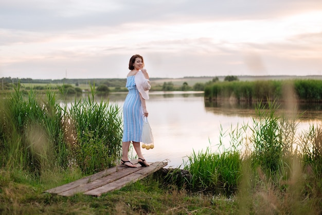 Hermosa mujer joven en el lago al atardecer