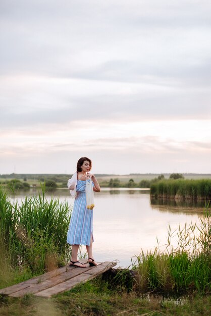 Hermosa mujer joven en el lago al atardecer