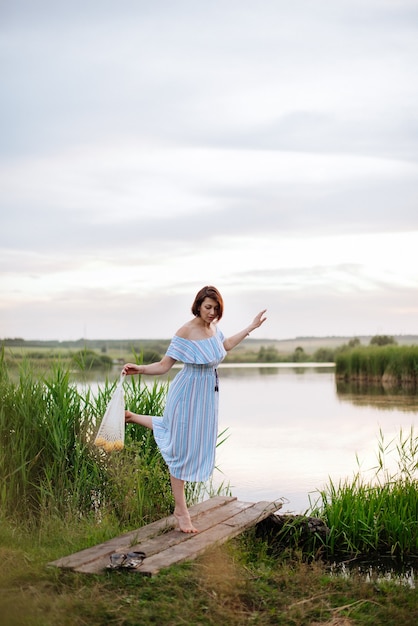 Hermosa mujer joven en el lago al atardecer