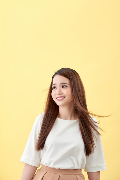 Hermosa mujer joven con largo cabello negro posando sobre fondo amarillo