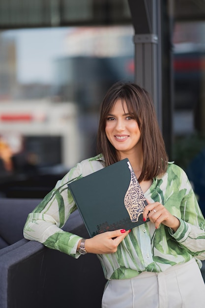 Hermosa mujer joven con un libro en sus manos Morena sonriente con un libro Concepto de estilo de vida de la gente