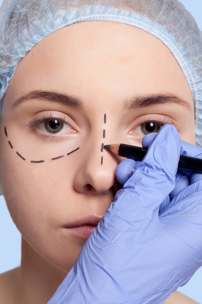 Foto hermosa mujer joven con líneas de perforación en el rostro antes de la operación de cirugía plástica