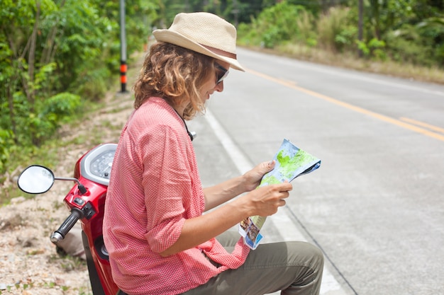 Foto hermosa mujer joven con mapa en mano y una moto en la carretera. viajes, navegacion, turismo